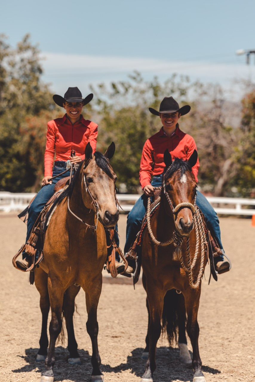 Hayley Bloomquist and a fellow rider side by side on horseback in western show clothes